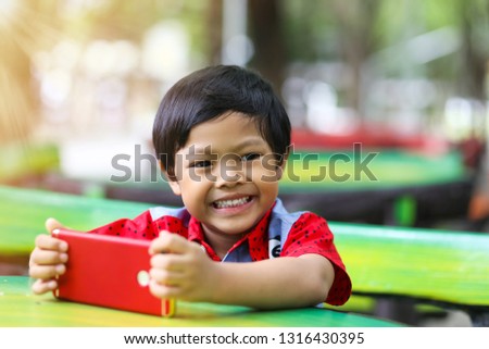 An Asian boy watching cartoon on a smart phone.