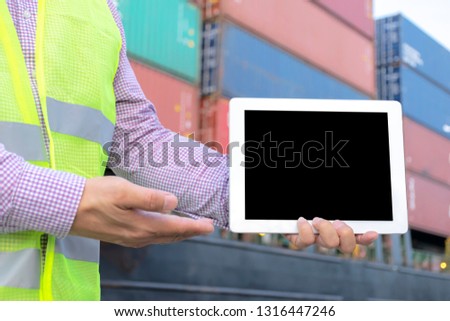 Logistic concept. Engineering is holding a tablet. Free space to be able to enter text or images to create an advertising media. The background is a large cargo carrying container.