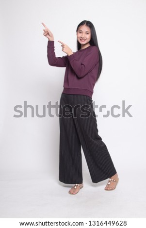 Full body of beautiful young asian woman pointing up on white background