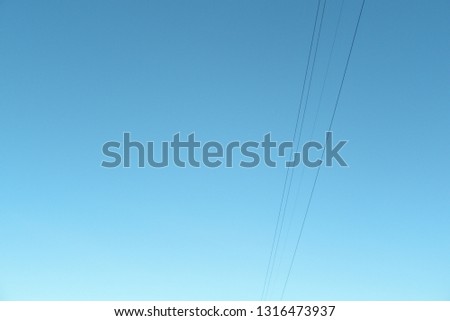 High-voltage electrical wires against the blue sky. High voltage transmission line. Bottom view