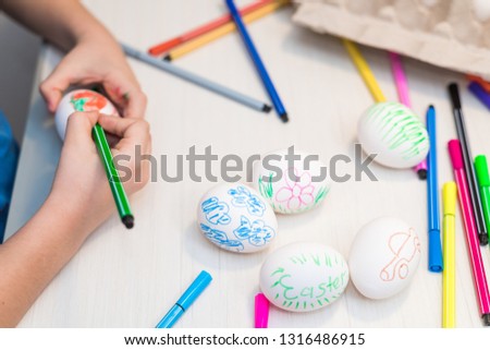 A child will paint Easter eggs with felt-tip pens. Easter ideas. Space for text. Egg tray. Happy easter.
