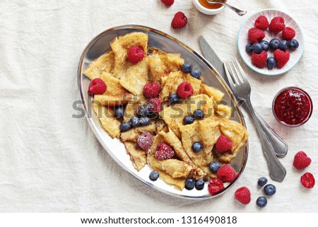 Crepes with fresh berries and raspberry marmalade. Thin pancakes with raspberry and blueberry. Overhead view