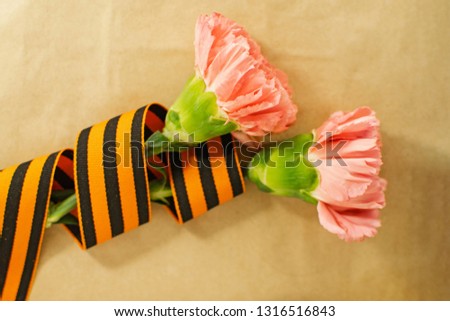 Pink Carnation with St. George ribbon on craft background, symbol of the great Victory, symbol of world war II.
