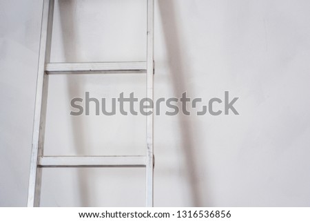 Aluminum ladder leaning against white wall. The concept of repair and construction