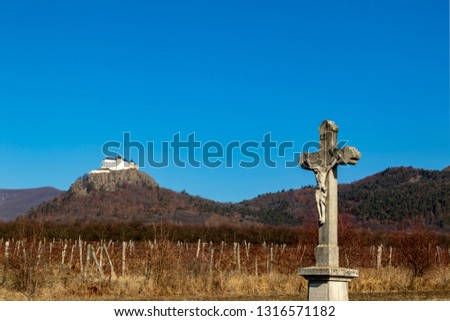 Old castle ruins and mountain top and religis cross in the foreground  with blue sky. Hungary, Fuzer Castle. European Heritage site
