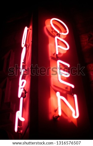 Red neon open sign glowing on black background