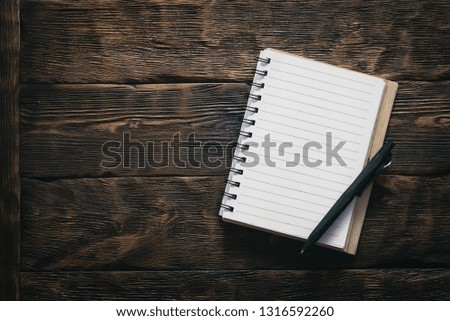 Blank notepad with empty paper sheets on the brown wooden table background.