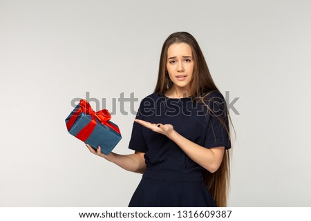 Photo of gorgeous european young girl having long brown hair, smiling and what inside gift box lying at her palm isolated over white background