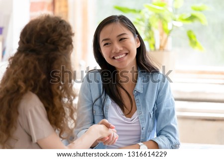 Young diverse friendly girls handshaking thanking for help in teamwork, smiling happy students interns coworkers shake hands celebrating successful cooperation, satisfied asian woman getting hired Royalty-Free Stock Photo #1316614229