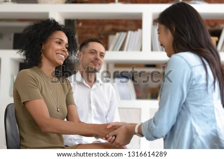 Asian and african women holding hands during group therapy session, diverse friends feeling reconciled relief smiling giving psychological support empathy overcome problem at psychotherapy counseling Royalty-Free Stock Photo #1316614289
