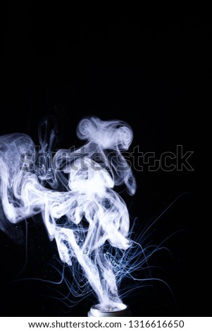 Vape smoke clouds isolated on black background. Hot vape liquid splash in vape coil. Nice aromatic cloud. Low light photo. Underexposed photo in a low key style. 