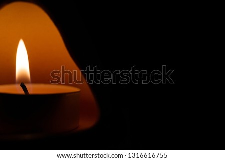 Underexposed low light photo of candle in aromatic lamp. Close-up view