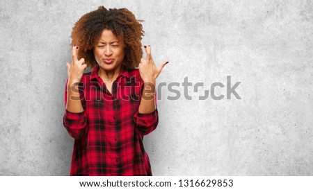 Young black afro woman crossing fingers for having luck