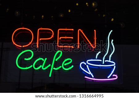 neon sign in window of Cafe coffee shop red and green letter blue and purple steaming cup of coffee icon