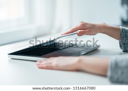 Close-up image of female hands open or close laptop on white table. Royalty-Free Stock Photo #1316667080