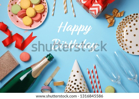 Flat lay composition with party items and text Happy Birthday on blue background