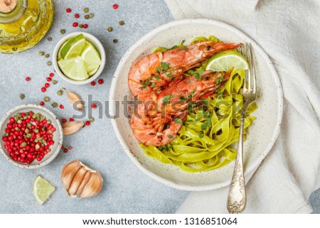 Fried king prawns with garlic, pepper, lime and parsley (cilantro). Large shrimp. Langoustine. Delicious dinner with pasta tagliatelle of spinach. Selective focus