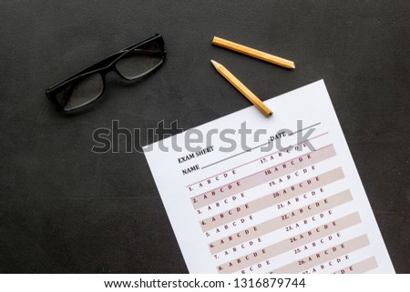 On the exam. Exam sheet, answer near glasses and pencil on black background top view