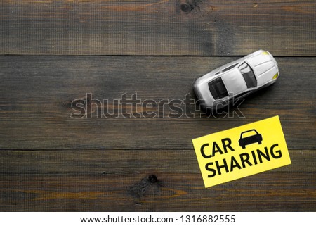 Carsharing concept. Toy car near text car sharing on dark wooden background top view space for text