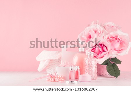 Elegant pink skin and body care products - cream, rose oil, liquid soap, salt, cotton towel and box - cosmetic accessories, romantic flowers on white wood table, copy space.