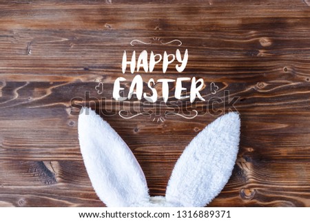 white rabbit ears with Happy Easter lettering inscription on a wooden background