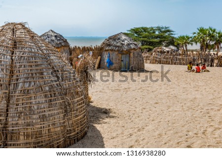 Partial view of traditional round bomas of semi-nomadic Turkana people, on shores of Lake Turkana, Kenya. The small dwellings are constructed from doum palm fronds, animal skins, timber. Copy space. Royalty-Free Stock Photo #1316938280