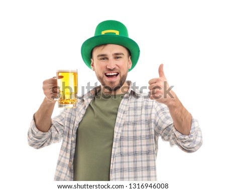 Handsome young man in green hat and with mug of beer showing thumb-up gesture against white background. St. Patrick's Day celebration
