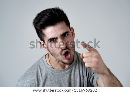 Close up portrait of young violent man with angry face looking furious and crazy showing fits and pointing finger at the camera. Human facial expressions, emotions and behavioral problems concept. Royalty-Free Stock Photo #1316969282