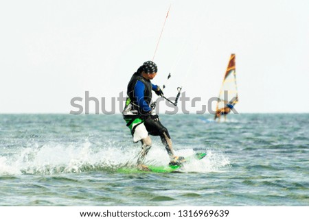 Kitesurfing and windsurfing action photos. Man rides a kite on windsurfer background. Selected focus