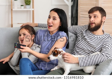 Family watching TV while sitting on sofa at home