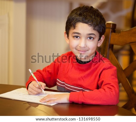 Little Boy Sitting at a Table and Doing His Homework