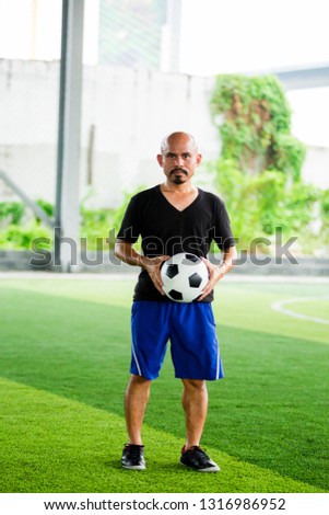 soccer player holding ball in hands after playing on green artificial turf