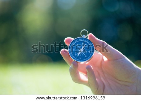 Young man on an adventure is holding a compass in his hand for finding is route