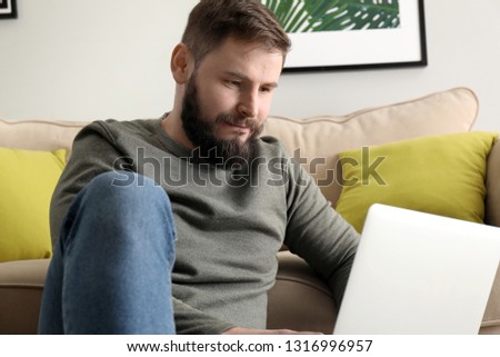 Bearded man working on laptop at home