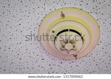 Old and dirty smoke detector with cobwebs on ceiling wall. Fire alarm system in house doesn't work. Emergency equipment in apartment need to clean and maintenance service. Carbon monoxide sensor. 