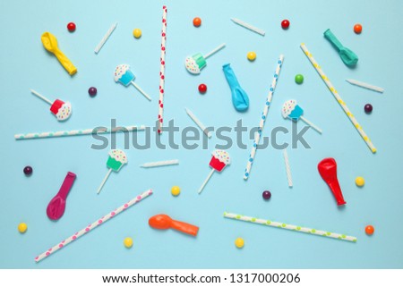 Children's cheerful decor for a party, blue background. Sweet candies, bright balls, festive candles and straws.