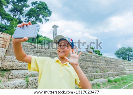 Happy young boy traveler making selfie. Famous Archaeological Site of Olympia. Peloponnese, Greece. Travel concept