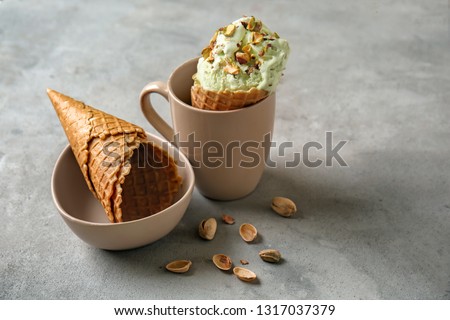 Waffle cones with delicious ice cream in cup on grey table
