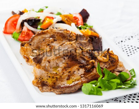 Cooked fried pork meat chops with salad of fried orange and vegetables