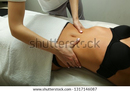 masseur doing massage of the muscles. the hands of a masseur do massage the abdomen closeup. photos for advertising massage services. anti-cellulite massage close-up.     