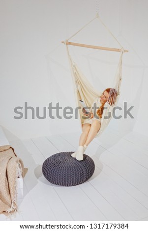 A girl with a tablet sits in a hammock / copy space
