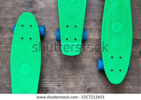 Three green skateboards on wooden background, top view