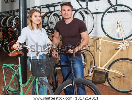 Portrait of male with smiling female who are standing satisfied in the bike store.