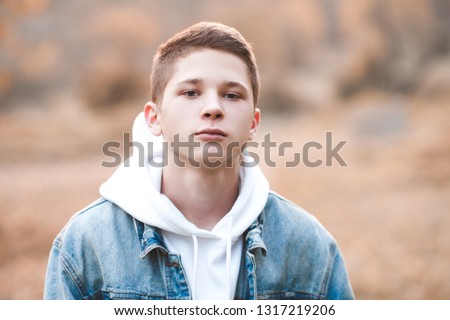Handsome blond teen boy 16-17 year old wearing hoodie and denim jacket outdoors. Looking at camera. Spring season.  Royalty-Free Stock Photo #1317219206