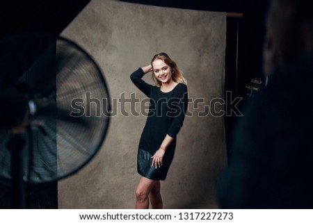 Beautiful model In dark clothes posing for photographers indoors 
