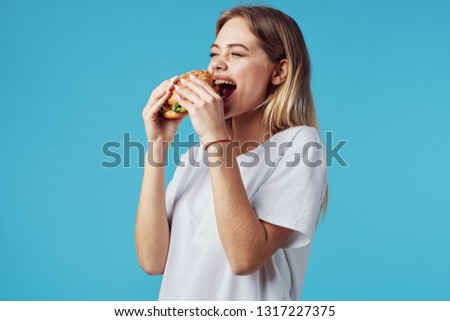 happy woman in white t-shirt eats hamburger