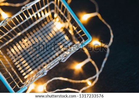 empty shopping cart on concrete desk surrounded by fairy lights, concept of online marketing and customer purchases