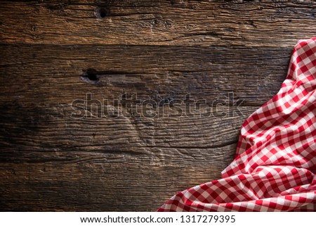 Red checkered kitchen tablecloth on rustic wooden table.