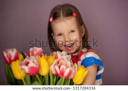 Rub a happy cute little girl 3-4 years old, holding a bouquet of tulips. Girl with tulips. Mother's Day, March 8, International Women's Day