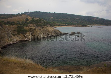 Amazing landscape of rocks and clear blue sea with hills, Mediterranean vegetation and wild beach in the background at the sunrise in the touristic place Sarti on Sithonia peninsula before the rain.